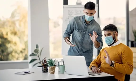 businessmen with face masks waving during video call laptop office